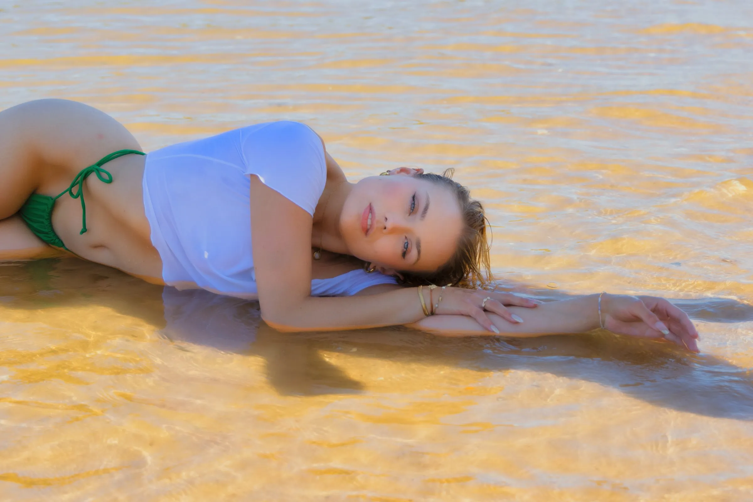 Junge Frau liegt auf dem Bauch im flachen Wasser, weiches Licht erzeugt eine ruhige Stimmung.