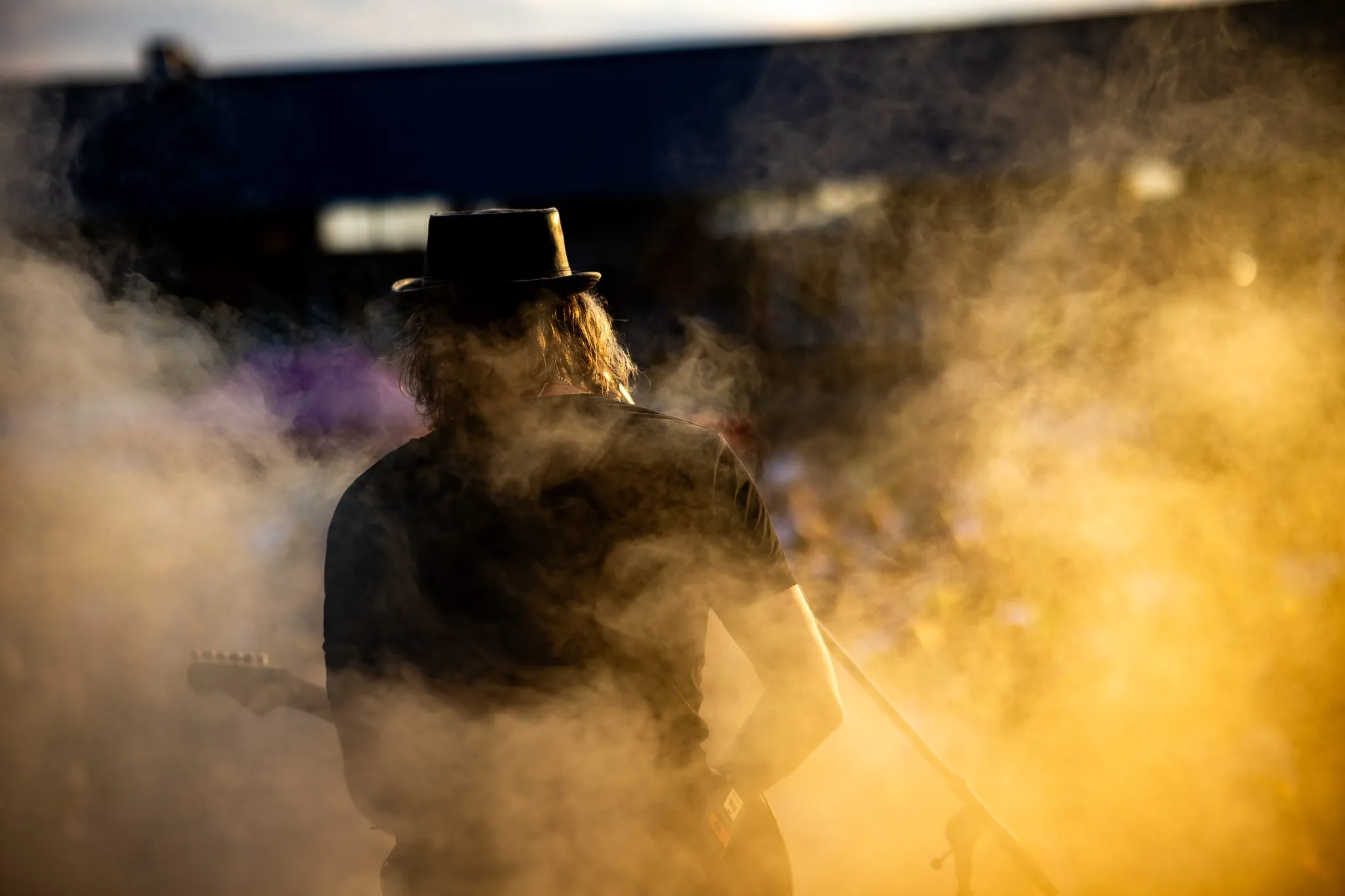 Weitläufige Menschenmenge bei goldenem Abendlicht, entspannte Festivalstimmung mit Sommerkleidung und Getränken in der Hand.